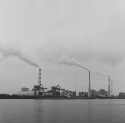 a black and white photo of smoke billowing from a factory