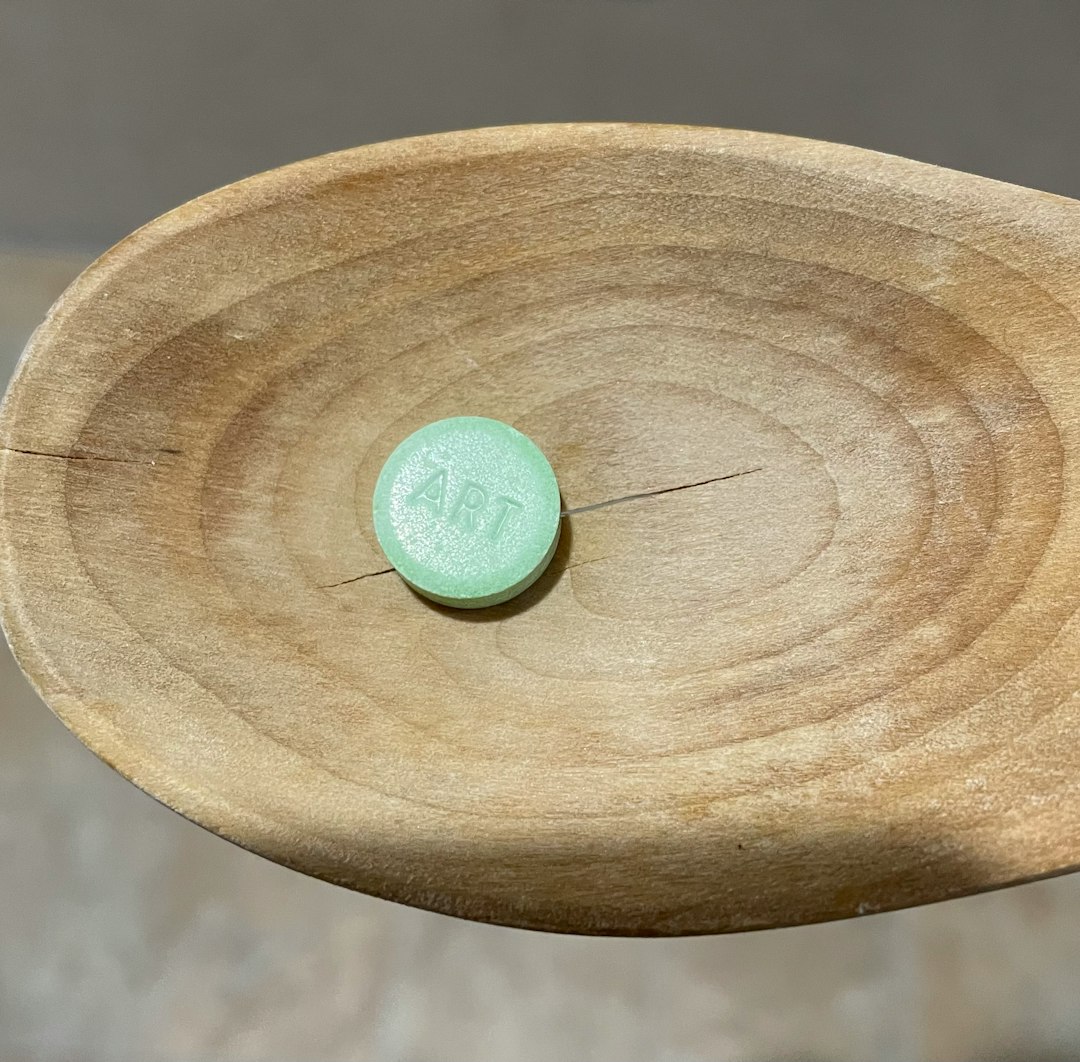 a wooden spoon with a green button on it