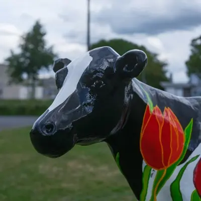 A black and white cow statue decorated with tulips